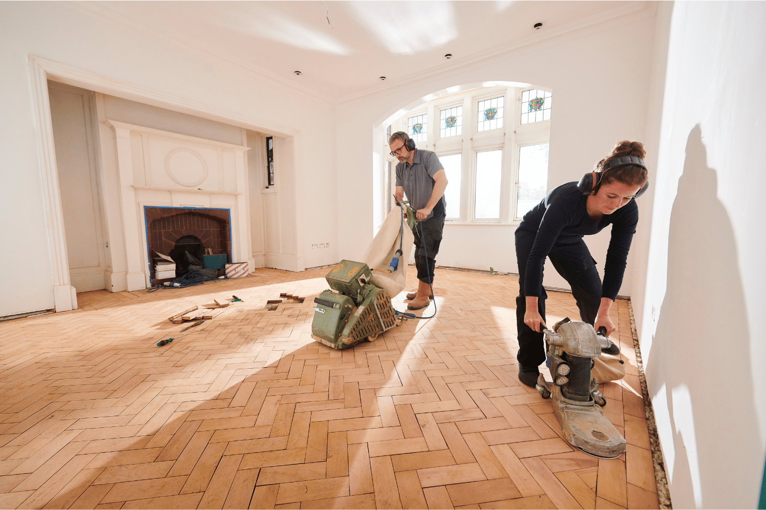 Man and women sanding living room floor