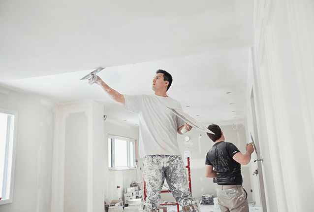 Two men plastering a room
