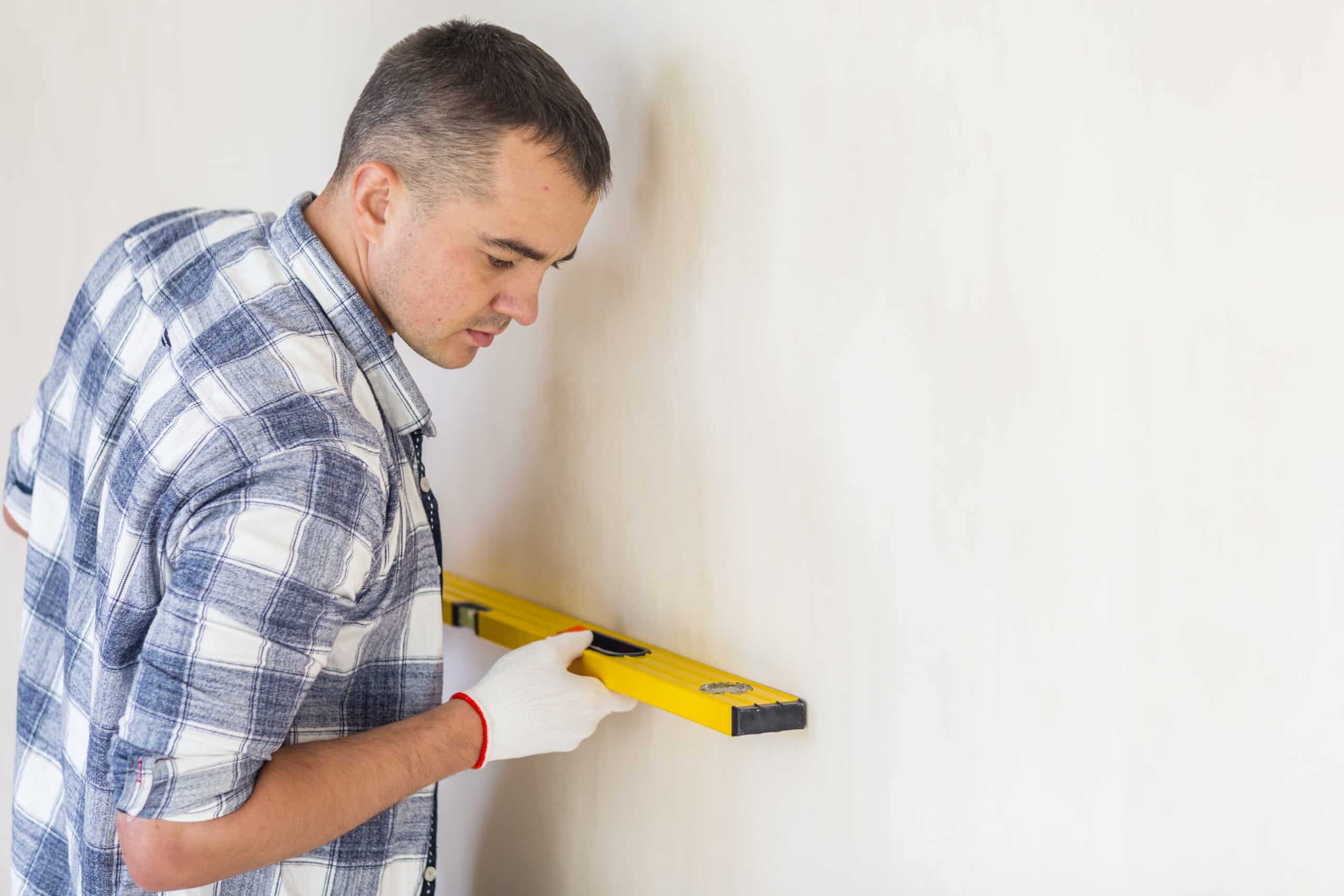 Man using spirit level to measure wallpaper line