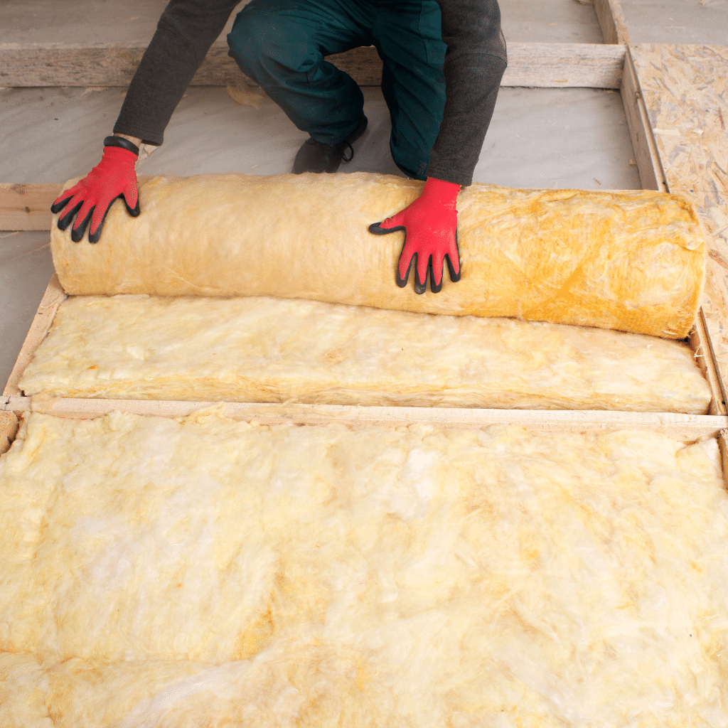 Person wearing red gloves laying loft insulation