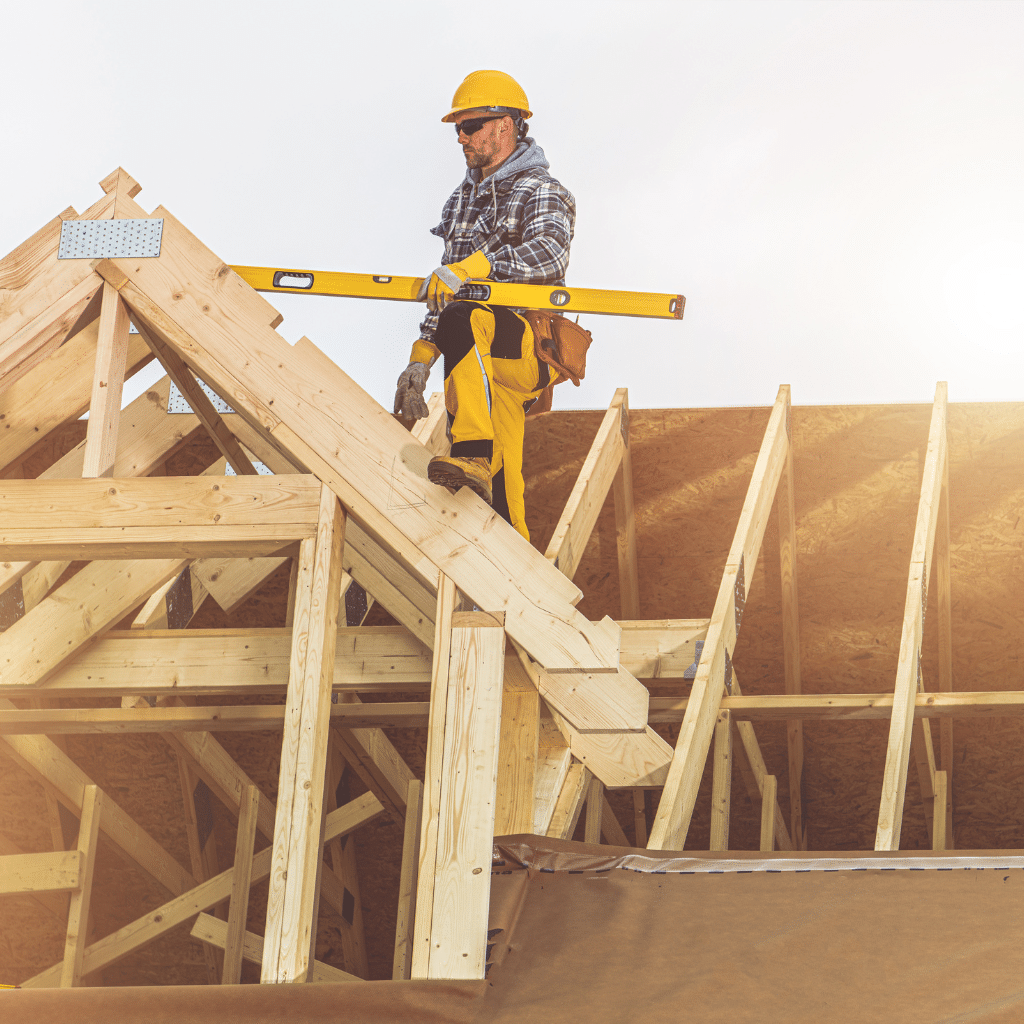 Builder holder spirit level on top of house roof extension, sunny backdrop